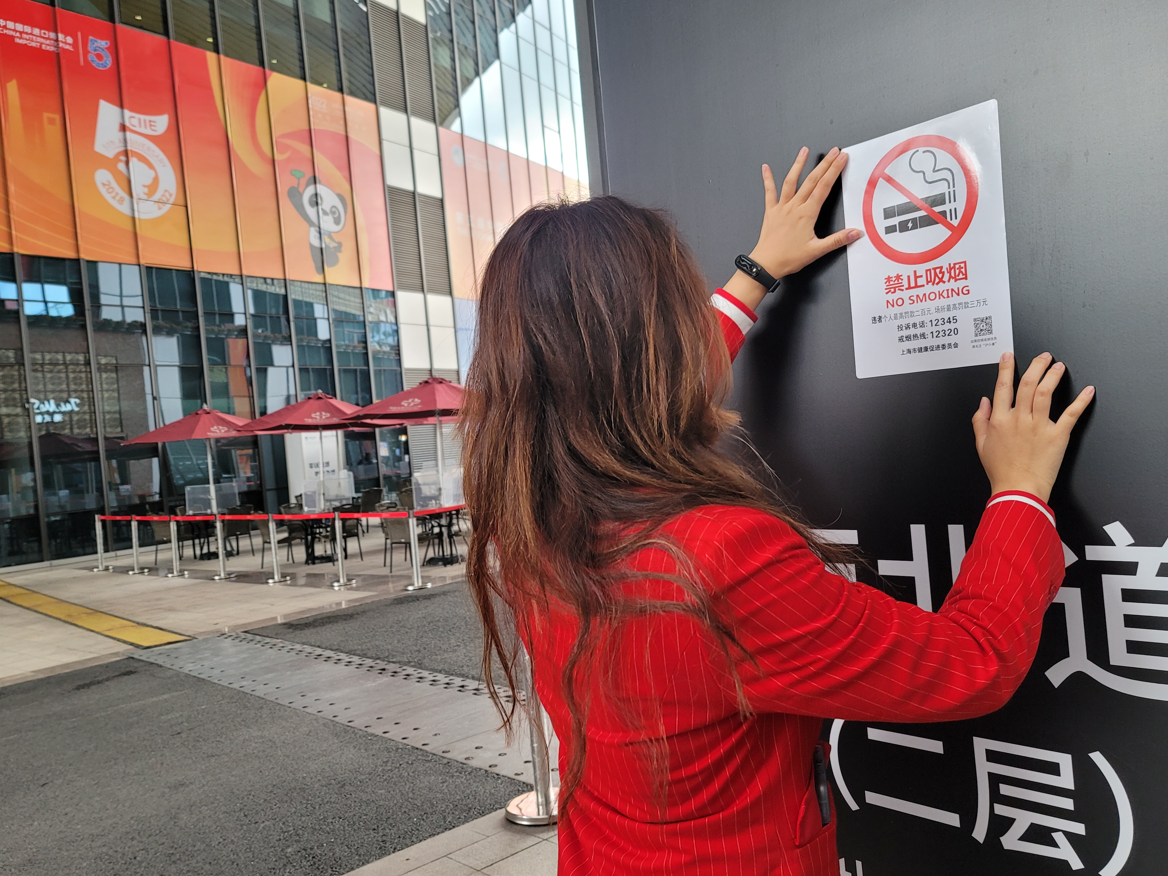 2022年10月28日《上海市公共场所控制吸烟条例》第二次修订，将电子烟纳入公共场所禁烟范围后的首届进博会，志愿者在张贴新版禁烟标识.jpg